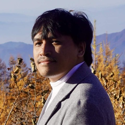 Everaldo Sembiring outdoors among autumn larches, mountains behind